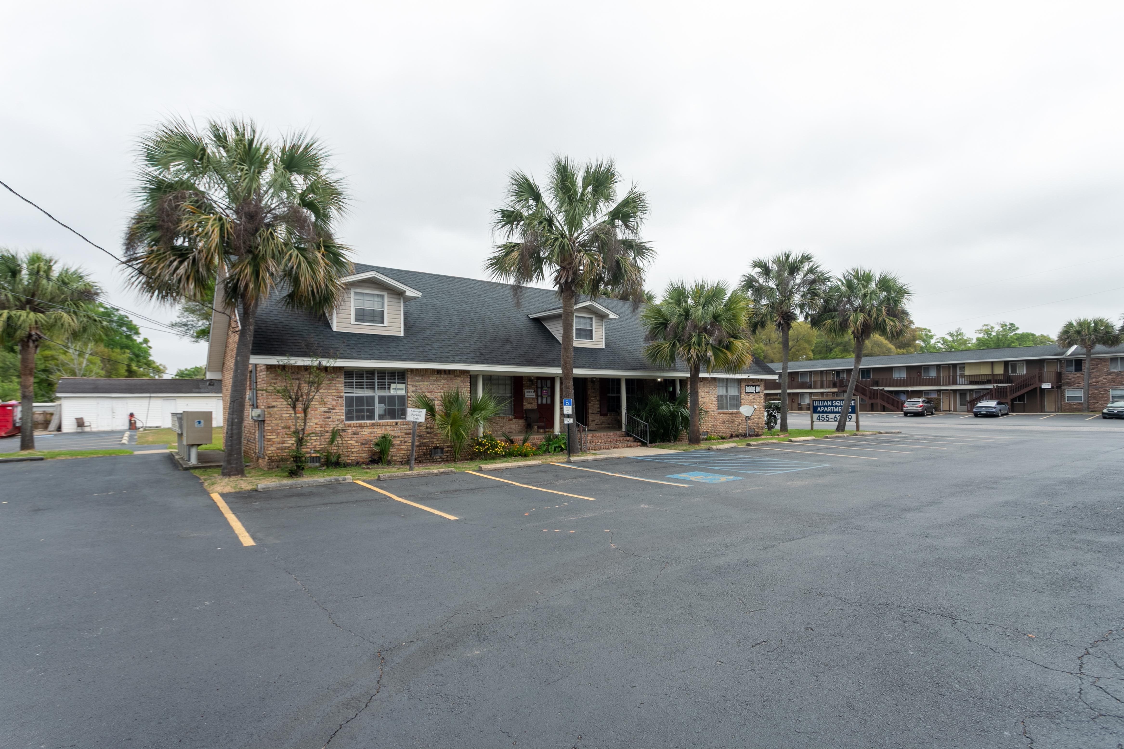 A parking lot with a building and palm trees in the background.